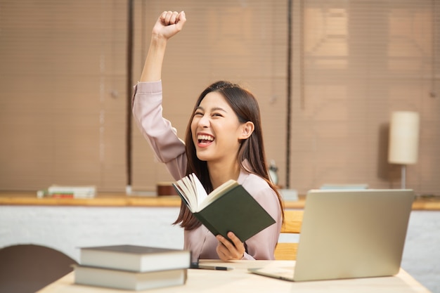 Young asian woman feeling happy and excited while reading book for start small business at home Premium Photo