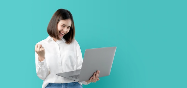 Young asian woman smiling holding laptop computer with fist hand and excited for success. Premium Photo