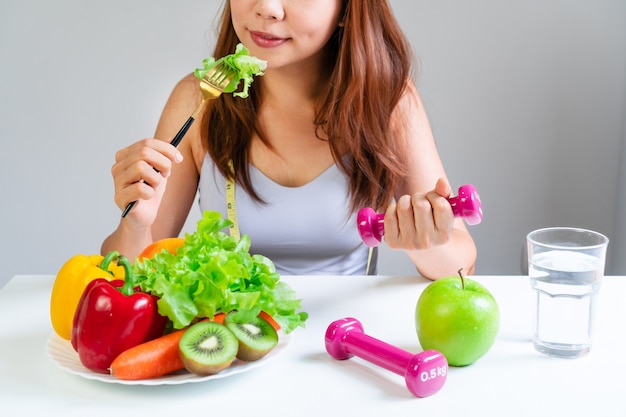 Premium Photo Young Asian Women Eating Vegetable While Holding Dumbbell With Fruits 