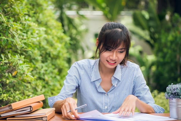 Young asian women writing homework on desk in outdoors, woman working with happy emotion concept. Vintage effect style pictures. Free Photo