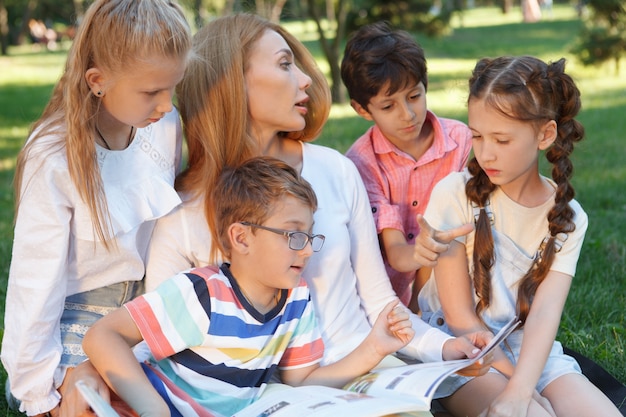 Young attractive female teacher reading a book to her little students Premium Photo