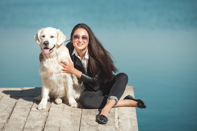 Premium Photo | Young attractive woman sitting at the pier with her dog ...
