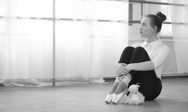 Premium | ballet on a warm-up. the ballerina is preparing to perform in the studio. a in ballet clothes and shoes kneads by handrails.