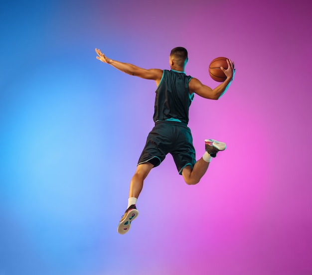 Young basketball player in motion on gradient studio background in neon light Free Photo