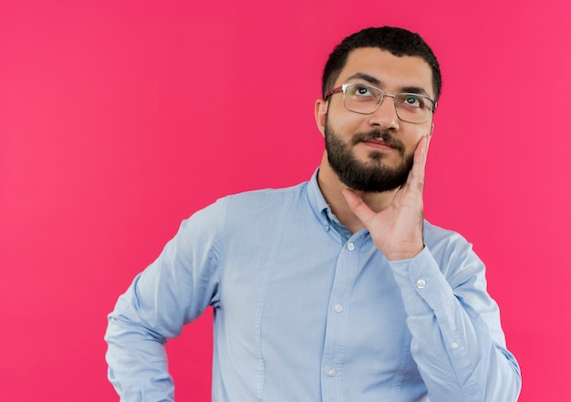 Free Photo Young Bearded Man In Glasses And Blue Shirt Looking Up Puzzled