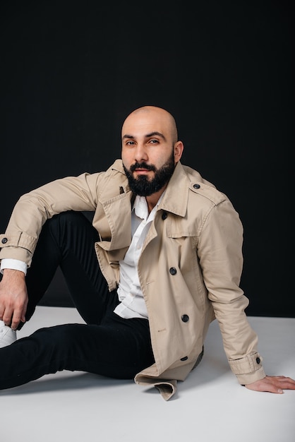 Premium Photo | A young bearded man sits on the floor in a raincoat on ...