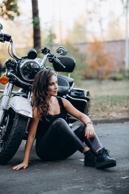 Premium Photo | Young beautiful biker girl in a black tank top and ...