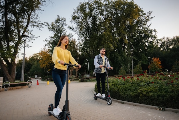 Premium Photo | A young beautiful couple rides electric scooters in the ...