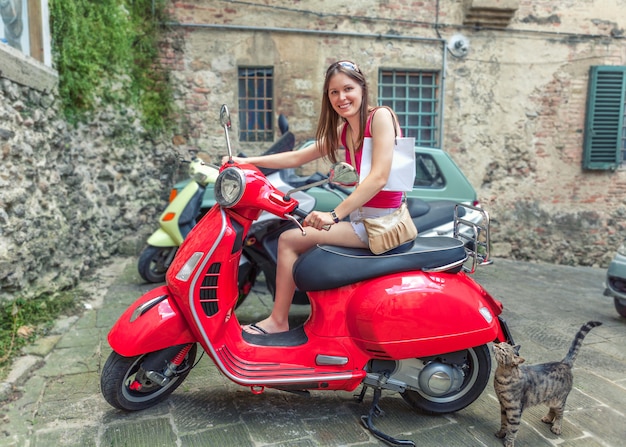 Premium Photo | Young beautiful girl rides a red motor scooter vespa ...