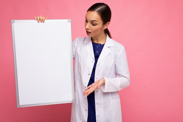 Download Premium Photo Young Of Beautiful Happy Brunet Woman Wearing Medical White Coat Holding White Magnetic Board For Mockup Isolated On Pink Background With Empty Space