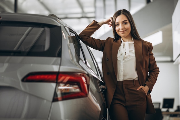 Young beautiful woman choosing car in a car showroom Free Photo