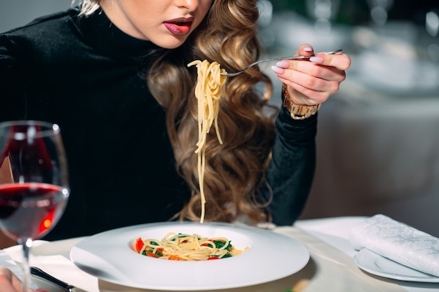Young beautiful woman eating pasta in a restaurant. Premium Photo