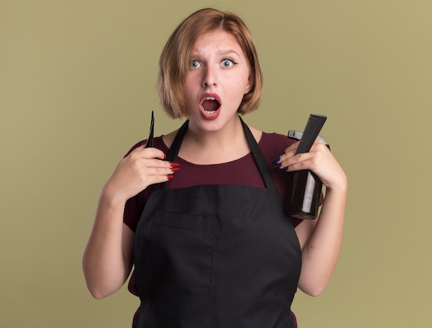 Free Photo | Young beautiful woman hairdresser in apron holding hair