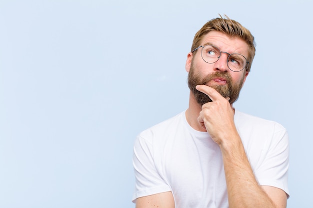 Premium Photo | Young blonde adult man thinking, feeling doubtful and confused, with different options, wondering which decision to make