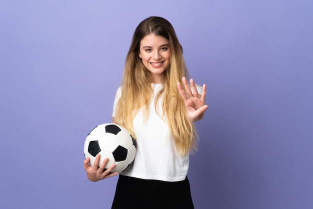 空白の壁に対して孤立したポーズをとって若い金髪のサッカー選手の女性 プレミアム写真