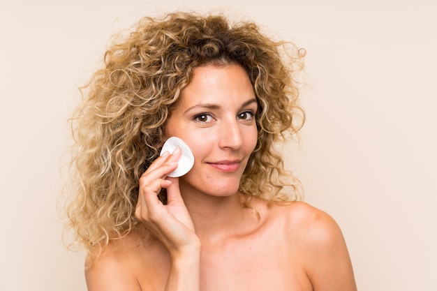 Young Blonde Woman With Curly Hair Removing Makeup From Her Face