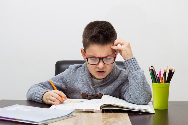 Young boy frustrated over homework, writing at home. Boy studying at ...