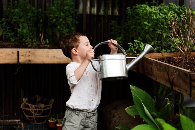 Premium Photo | Young boy watering plants in the garden