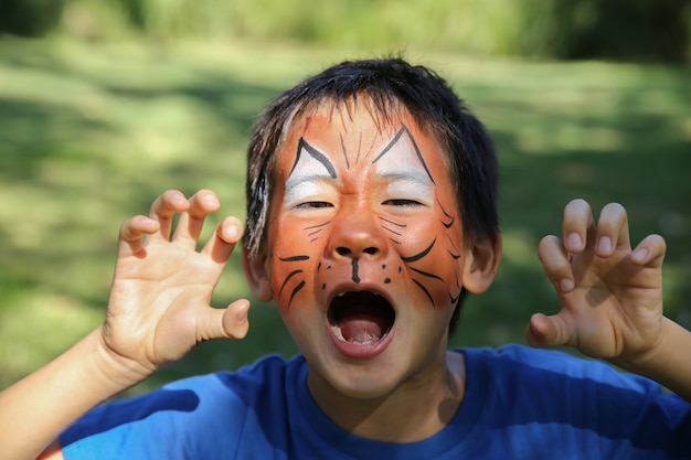 虎のように面白い顔の絵を描く若い少年 プレミアム写真
