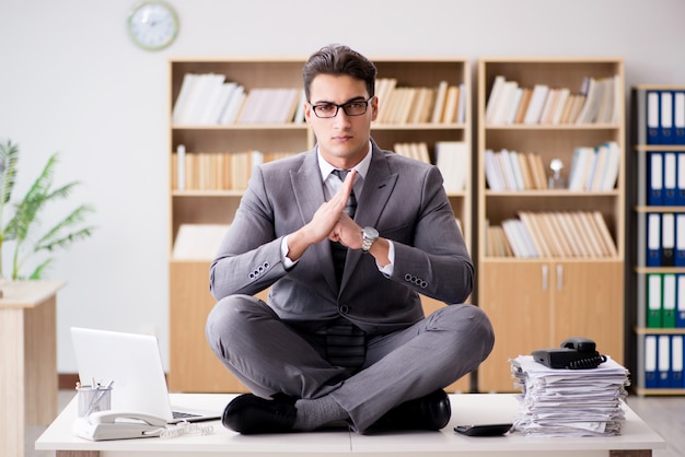 Premium Photo | Young businessman meditating in the office