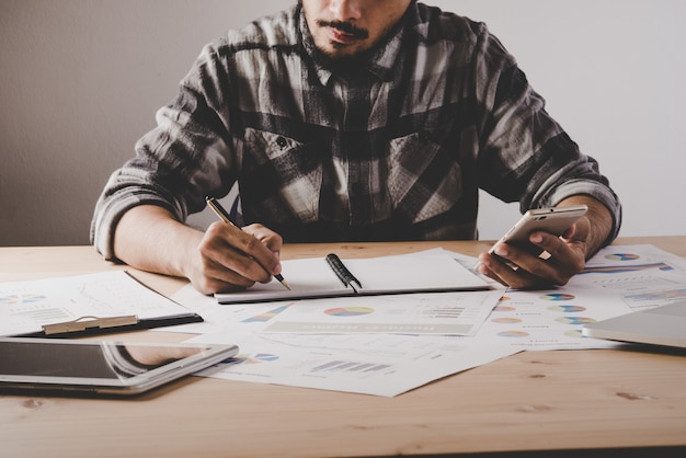 Young businessman writes in a notebook while working analysis business data in office. Free Photo Young businessman writes in a notebook while working analysis business data in office. Free Photo