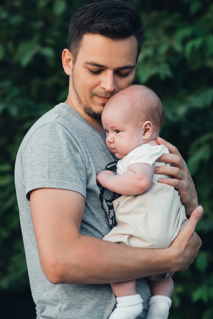 ひげを持つ若い白人の父は生まれたばかりの赤ちゃんの男の子の息子を抱擁します プレミアム写真