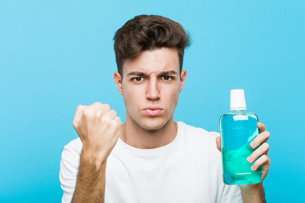 Young caucasian man holding a mouthwash showing fist Premium Photo