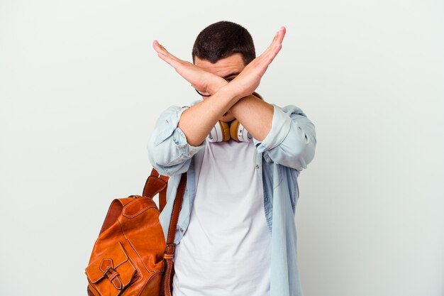 Young caucasian student man listening to music on white keeping two arms crossed, denial concept. Premium Photo