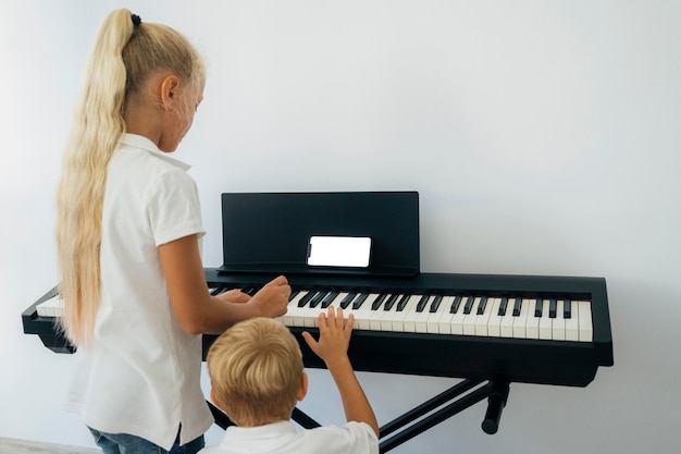 Young children learning how to play piano Free Photo
