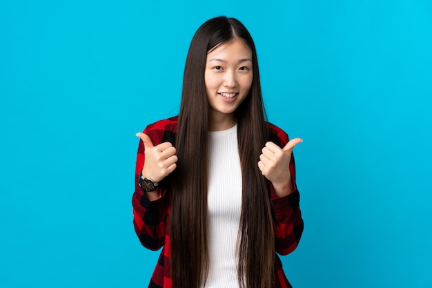 Premium Photo | Young chinese girl on isolated blue with thumbs up ...