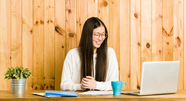 Young Chinese Woman Studying On Her Desk Laughs And Closes Eyes