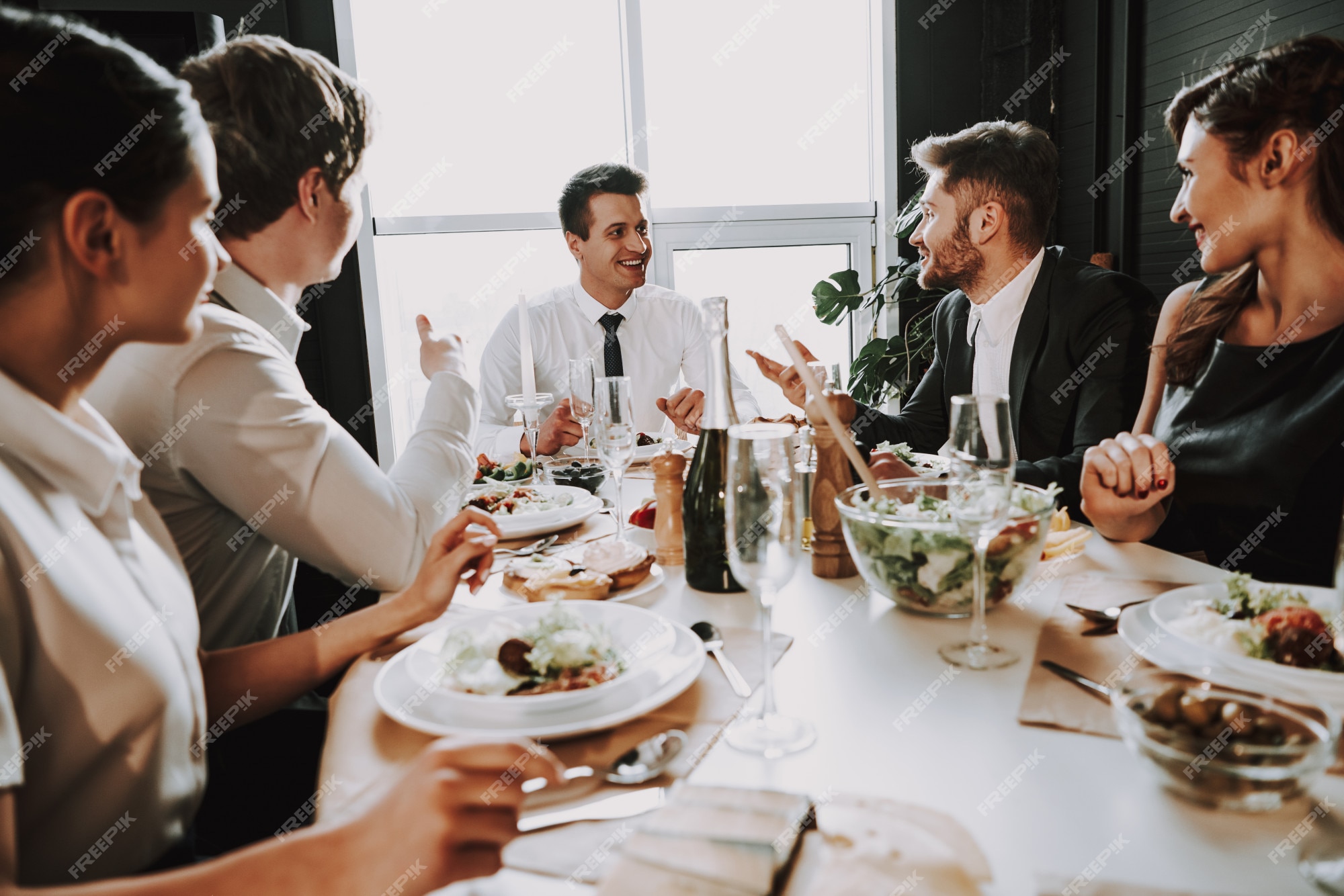 Premium Photo | Young company sits in suits around dinner table