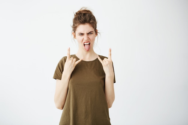 Young Cool Woman With Bun Showing Tongue And Rock Sign Free Photo