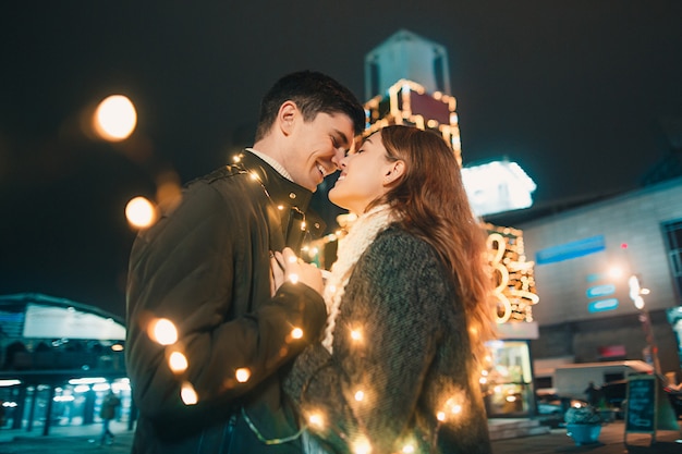 若いカップルがキスをし クリスマスの時に夜の街で屋外を抱いて 無料の写真