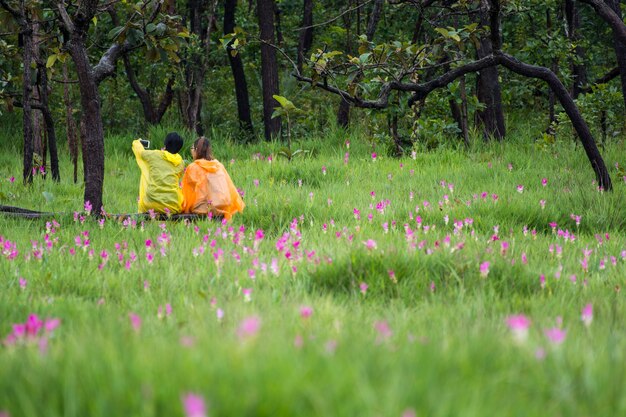 若いカップルの男とピンクの花畑でセルフをしている女性 プレミアム写真