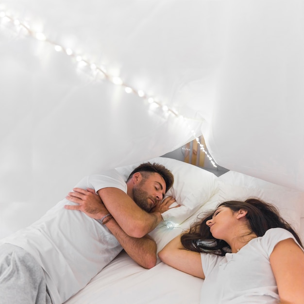 Young Couple Sleeping On Bed Under Illuminated Whit