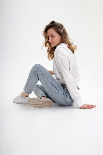 Premium Photo Young Cute Pensive Caucasian Girl Posing In White Shirt Blue Jeans At Studio