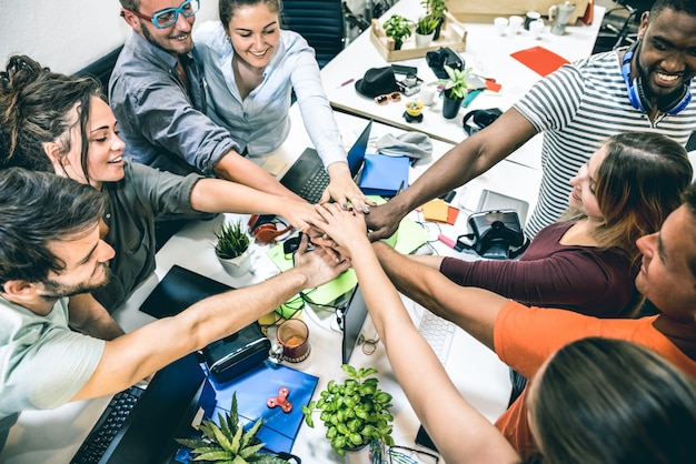 Young employee startup workers stacking hands at studio on entrepreneurship brainstorming project Premium Photo