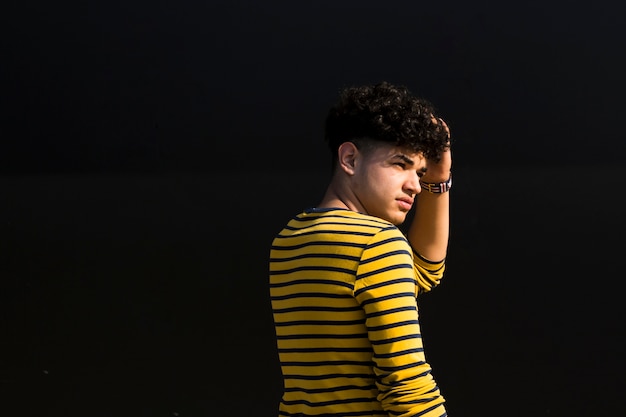 Young ethnic man with curly hair in striped shirt looking ...