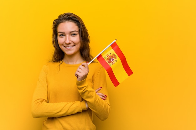 Young european woman holding a spanish flag smiling confident with crossed arms. Premium Photo