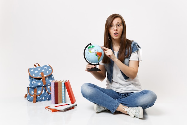Negara Studi Ini Menerima Kamu yang Belum Pintar Bahasa Inggris Young excited amazed woman student holding globe pointing index finger on country, place sitting near backpack, school books isolated Free Photo