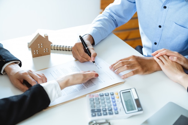 Young family couple signing home loan contract purchase agreement with property real estate agent Premium Photo