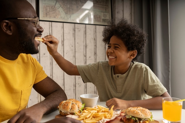 Premium Photo | Young father and son having burgers and french fries ...