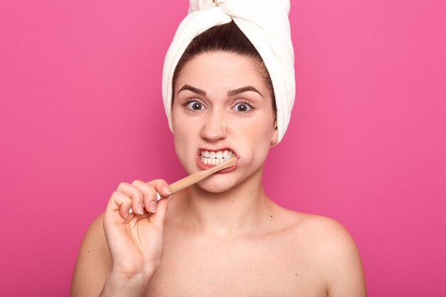 Young female brushing her teeth with efforts, having ...