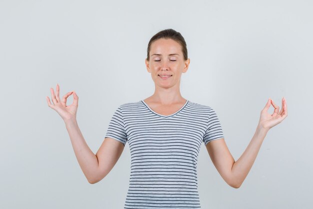 Free Photo | Young female doing meditation with closed eyes in striped ...