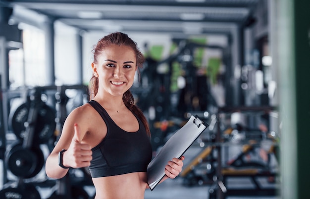 Premium Photo | Young female fitness personal trainer with notepad ...