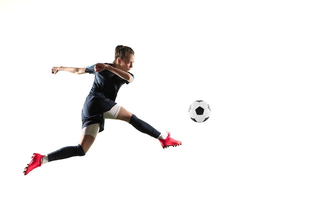 スポーツウェアとブーツで長い髪の若い女性のサッカー選手またはサッカー選手は 白い背景で隔離のジャンプでゴールのためにボールを蹴ります 健康的なライフスタイル プロスポーツ 趣味の概念 無料の写真