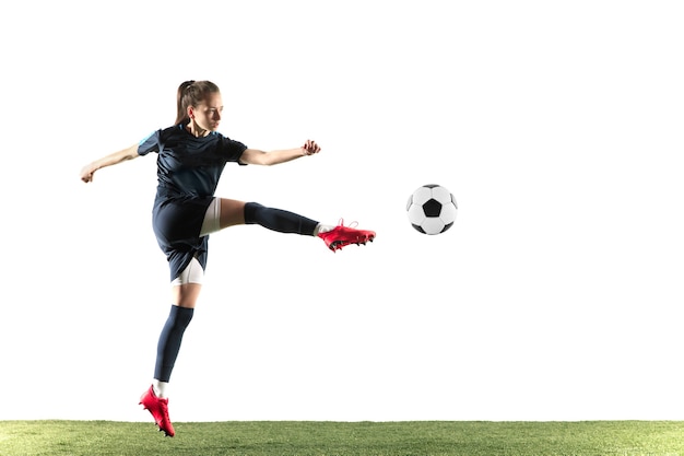 スポーツウェアとブーツの長い髪の若い女性のサッカー選手またはサッカー選手は 白い背景で隔離のジャンプでゴールのためにボールを蹴ります 健康的なライフスタイル プロスポーツ 趣味の概念 無料の写真