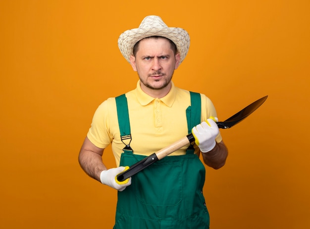 Free Photo | Young gardener in jumpsuit and hat holding shovel looking ...