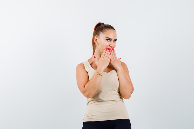 Free Photo | Young girl in beige top, black pants covering mouth with ...